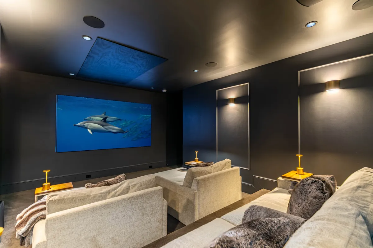 A home theater setup with a massive projection screen displaying an aquatic scene, surrounded by comfortable theater-style seating and ambient lighting. The arrangement creates a true cinema-like experience for viewers.